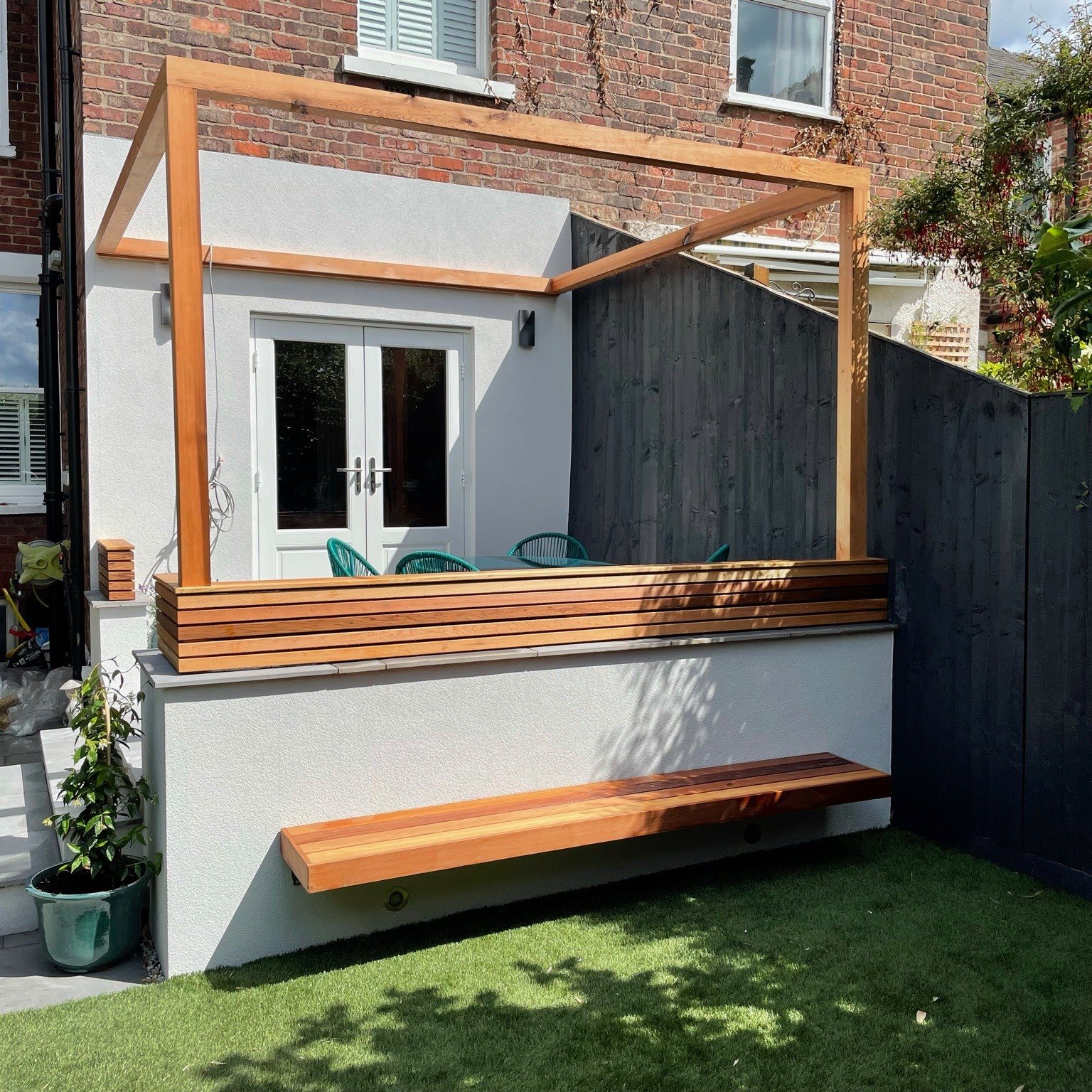 Timber frame and floating bench against a rendered wall